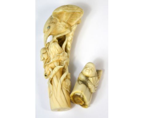 A 19th century ivory netsuke in the form of a man holding a fan and a 19th century parasol handle carved with a crane in foli