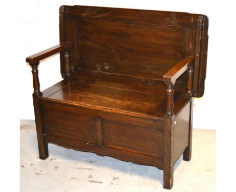 An early 20th century oak monks bench of simple form with lift up seat on block supports, width 110cm.