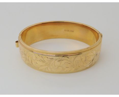 A 9ct gold wide engraved bangle, inner dimensions 6.5cm x 5.9cm, weight 31.1gms Condition Report: Available upon request