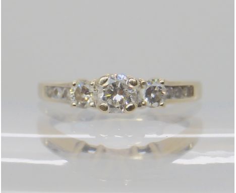 A 14k white gold diamond three stone ring with further smaller diamonds to the shoulders estimated approx diamond content 0.5