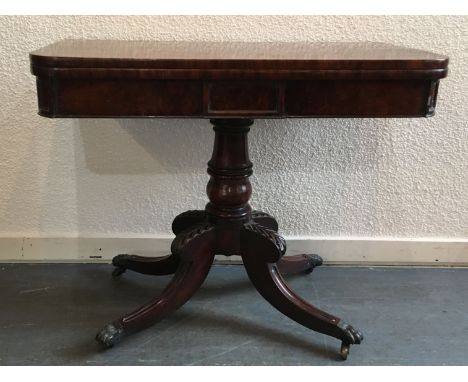 A FIGURED MAHOGANY CARD TABLE  on carved quatrefoil base with brass lion paw casters, 91cm wide