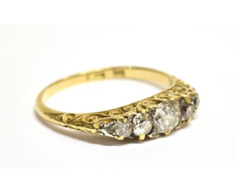 A LATE VICTORIAN GOLD AND DIAMOND FIVE STONE CARVED HALF-HOOP RING with rose diamond points, the principal graduated cushion-