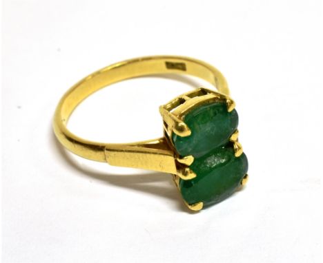 A VINTAGE GOLD AND EMERALD TWO STONE RING  the two oval mixed-cut stones of slightly differing sizes claw set between split s