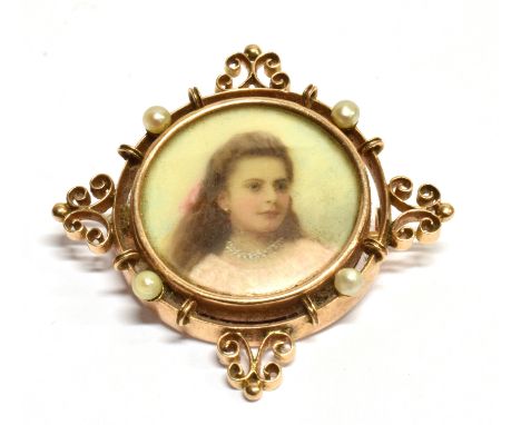 AN EDWARDIAN GOLD AND SEED-PEARL LOCKET-BACK BROOCH The central round glazed locket enclosing a portrait of a girl within a w