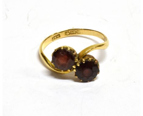 AN 18CT ROSE GOLD AND GARNET TWO STONE CROSS-OVER RING the round mixed-cut stones claw set to a 'D' section shank, the marks 