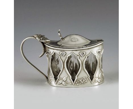 Henry Wilkinson, Birmingham 1909, an Arts and Crafts silver mustard pot, pierced oval cylinder form, embossed with floral spe