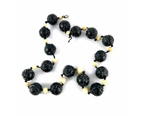 A Chinese carved black jade and ivory bead necklace, decorated with zoomorphic and character symbols, 63cm long