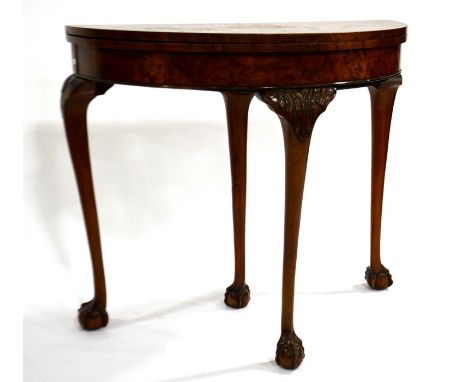 A 1920s walnut and burr veneered demi lune fold over card table, on extendable drawer action support, four carved cabriole ba