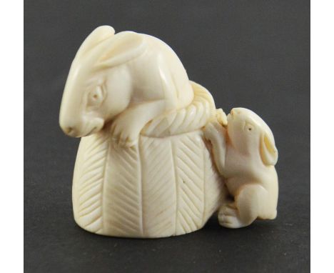 A 19th century Japanese ivory netsuke, Meiji, modelled as a rabbit and kit in a basket, 4cm