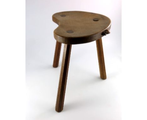 Robert Mouseman Thompson of Kilburn, an Arts and Crafts oak cow stool, the kidney shaped seat supported on three octagonal se