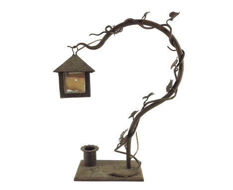 An Art Nouveau wrought iron table lamp, naturalistically modelled as a branch entwined with ivy, supporting a four paned lant