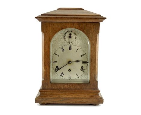 A large 1930s Continental oak cased mantle clock, Kienzle, having a 6" silvered dial with Roman hours, within engraved dial w