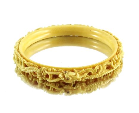 λ A 19th century Chinese ivory bangle, circular form, carved dragons decoration, 9cm diameter