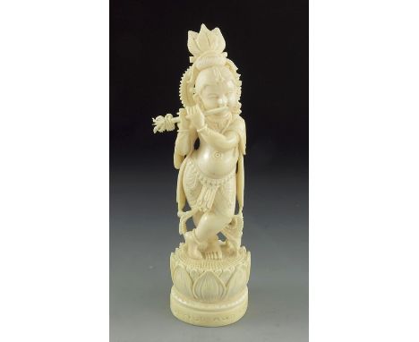 A 19th century Indian carved ivory figure of Krishna, playing the flute, on a lotus plinth, 17cm high