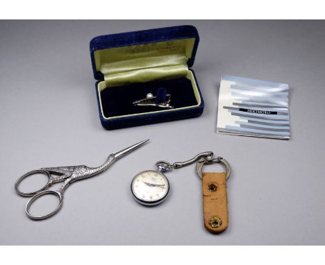 A pair of needlework scissors - modelled as a stork, together with a 20th century fob watch and a pearl mounted tie clip. (3)