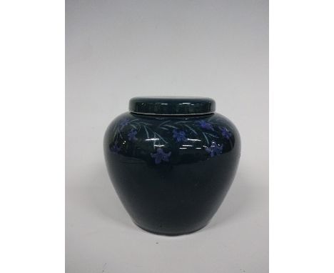 A RUSKIN POTTERY OVOID VASE AND COVER, having trailing blue flowers and leafage decoration to dark green ground, impressed Ta