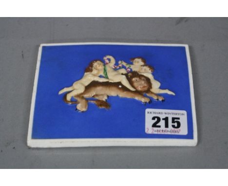 A RECTANGULAR CERAMIC PLAQUE, having hand painted relief decoration depicting cherubs with grapes on recumbent lion, having b
