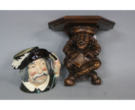 A LATE 19TH CENTURY STAINED WALNUT WALL BRACKET, in the form of a cross legged medieval man holding a sheet of music manuscri