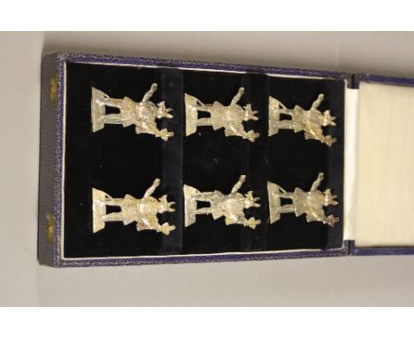 A CASED SET OF SIX EDWARDIAN MENU HOLDERS, cast in the form of a beast headed man holding tools, makers F.J.K, Chester 1916, 