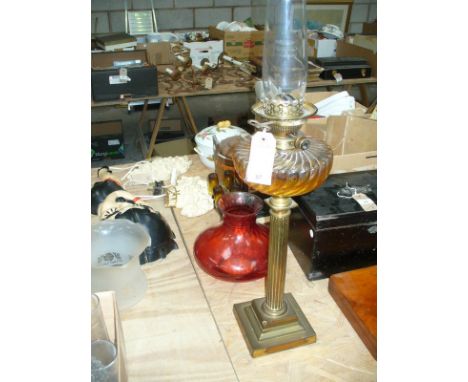 A Victorian Corinthian column oil table lamp with a spirally lobed glass reservoir raised on a stepped plinth base , with red