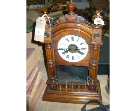 A late 19th Century walnut alarm mantle clock
The Gothic architectural casing with three campana urn finials, the hinged and 