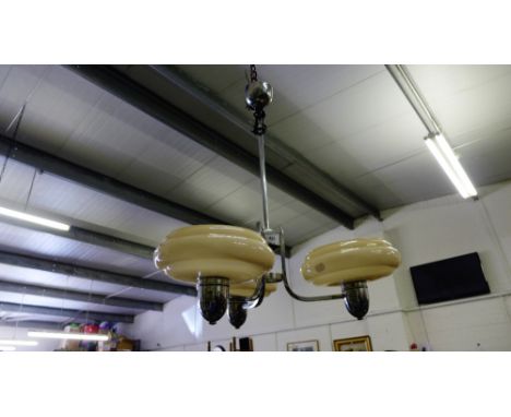 A chrome light fitting with three pale pink glass shades