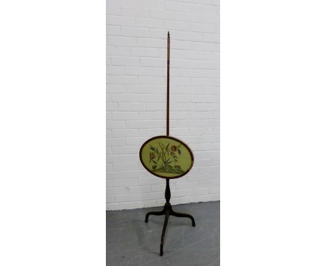A mahogany pole screen with an oval glass panelled tapestry screen on tripod supports, 148cm