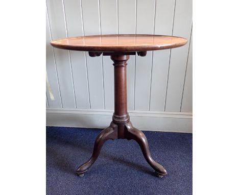 A GEORGE III MAHOGANY TRIPOD TABLE with tilting dished top in tapered turned column, the feet with brass and leather castors 