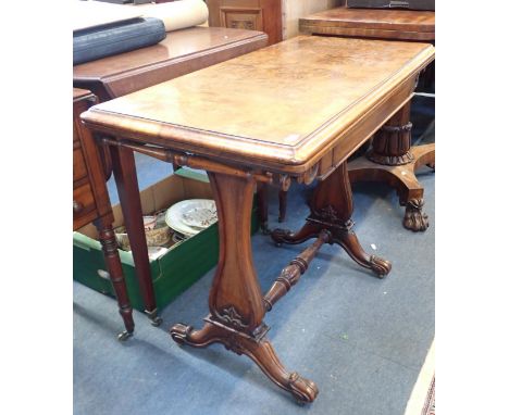 A VICTORIAN FIGURED WALNUT CARD TABLE with fold-over top, vase shaped supports and scrolling feet 92cm wide