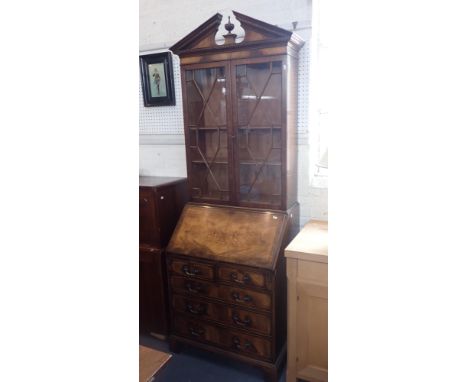 A REPRODUCTION FIGURED MAHOGANY BUREAU BOOKCASE with astragal glazing and 'broken' pediment with urn, by G.T. Rackstraw, Worc