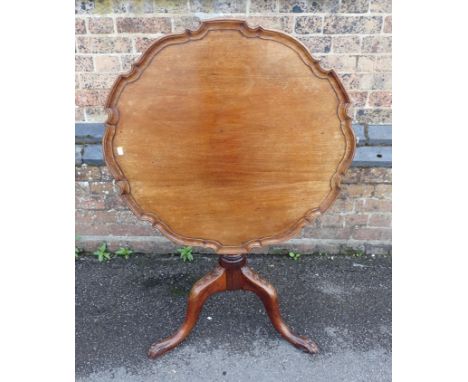 A GEORGE III MAHOGANY TRIPOD TABLE with 'pie crust' tip-up top and claw feet, with bellflowers to the knees 76cm dia