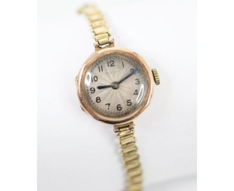 A 9ct yellow metal cased ladies wristwatch, the circular engine turned dial with Arabic numerals, dial 2cm wide, upon a base 