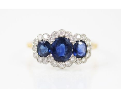 An Edwardian style 18ct yellow gold sapphire and diamond triple cluster ring, the central oval cut sapphire with smaller sapp