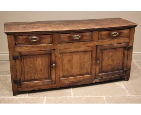 An early 18th century elm dresser base, the figured and moulded, oversailing top above an arrangement of three lip moulded fr