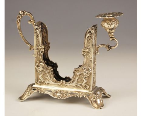 A continental silver chamber stick, late 19th century, with vacant central aperture for a book, with cherub, floral and folia