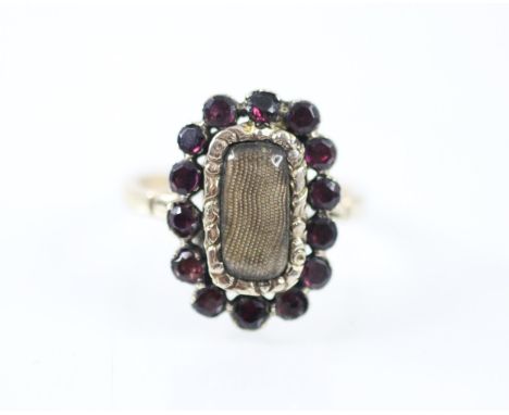 A Georgian style untested garnet mourning ring, the central rectangular glazed aperture within a surround of fourteen flat cu