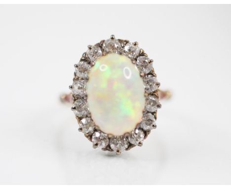 A 19th century style white opal and diamond ring, the central oval opal cabochon within a surround of fourteen old cut diamon