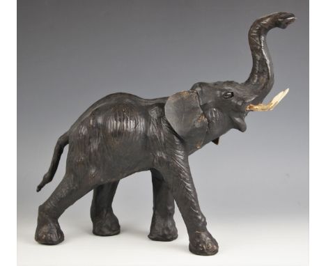 A leather covered elephant, 20th century, modelled with trunk raised, leather ears (possibly  later) with later carved wooden