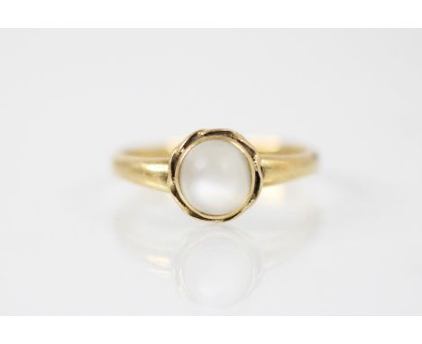 A moonstone and yellow metal ring, the circular moonstone cabochon within a yellow metal scrolling rubover mount, with plain 