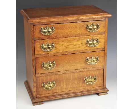 An Edwardian golden oak four drawer table top collectors chest, the moulded top over four long graduated drawers, applied wit