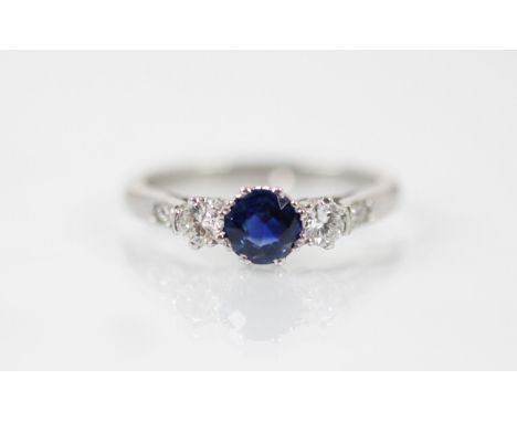 An untested sapphire and diamond three stone ring, the central round cut sapphire with a round cut diamond to each side, set 