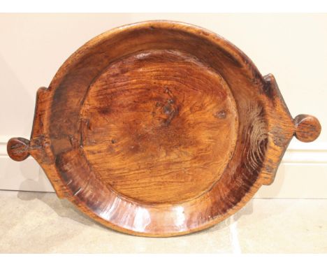 A 19th century dairy bowl, probably elm, the angular lug handles with roundel grips, 42cm diameter, 60cm with the handlesCond