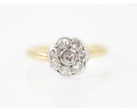 An Edwardian style diamond cluster ring, the eight round cut diamonds in a white metal rubover setting edge designed as a flo