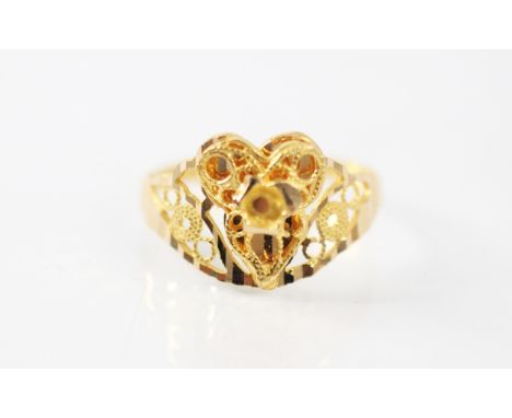 A yellow metal ring, the openwork head with applied cannetille style decoration with swirl detail, leading to a faceted shank