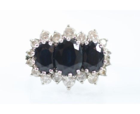 A sapphire and diamond triple cluster ring, the three oval cut sapphires each claw set within a surround of eighteen brillian