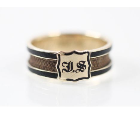 A 19th century mourning ring, the central channel with plaited hairwork, with black enamel border with central cartouche init