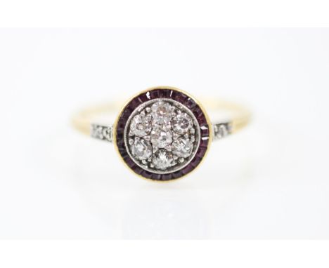 An early 20th century untested ruby and diamond target ring, the central seven old cut diamonds set in a white metal milgrain