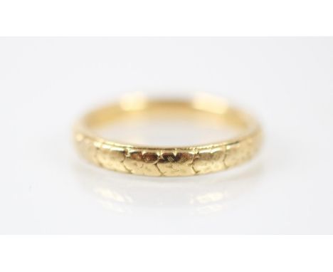 A yellow metal engraved wedding band, designed with continuous foliate decoration, stamped '18ct' ring size N, 5gms 