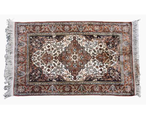 A small Persian silk rug the ivory field with central floral pendant medallion and all over floral and vine decoration, with 