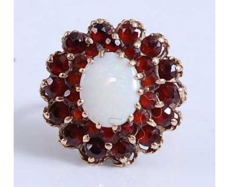 A 9ct yellow gold, opal and garnet oval cluster ring, featuring a centre oval opal cabochon within two borders each with 14 r